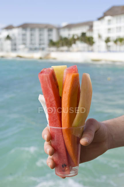 Male hand holding cup of tropical fruits on resort of Playa del Carmen, Quintana Roo, Mexico — Stock Photo