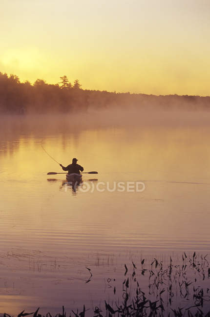 Silhouette of man fly-fishing from sea kayak, Lake Muskoka, Ontario, Canada. — Stock Photo
