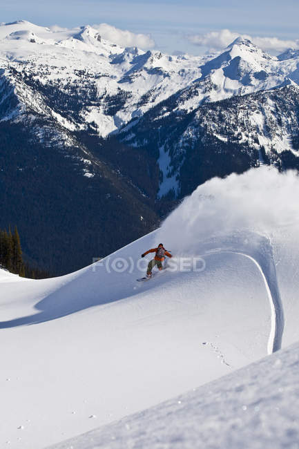 Backcountry snowboarder spray powder turn, Monashees, Vernon, British Columbia, Canadá - foto de stock
