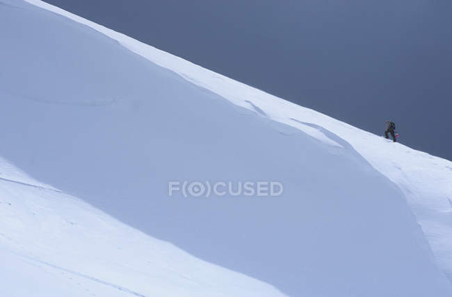 Man climbing ridgeline with snowboard in back country of Lake Louise, Alberta, Canadá . — Fotografia de Stock