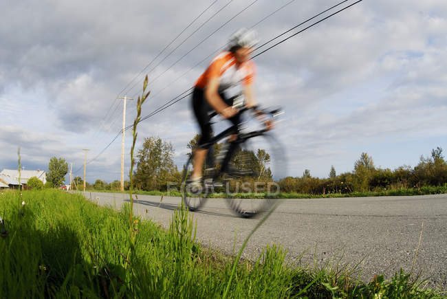 Неузнаваемый человек велоспорт на шоссе в Finn Slough, Ричмонд, Британская Колумбия, Канада — стоковое фото