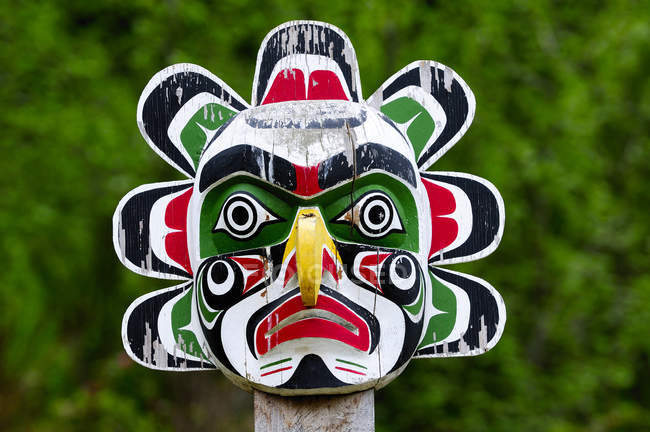 Weathered sun mask totem at burial ground on Cormorant Island, British Columbia, Canada. — Stock Photo