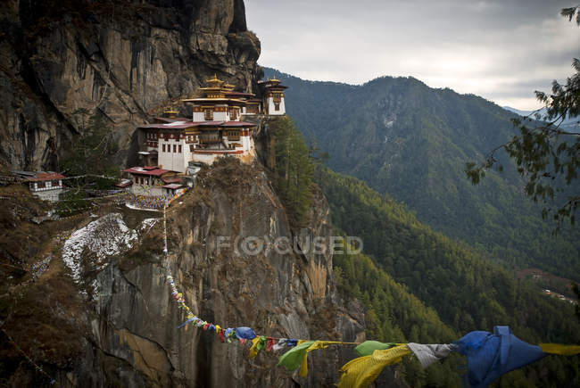 Bandeiras de oração e Taktsang Tigers Nest Mosteiro em rochas acima Paro, Butão — Fotografia de Stock