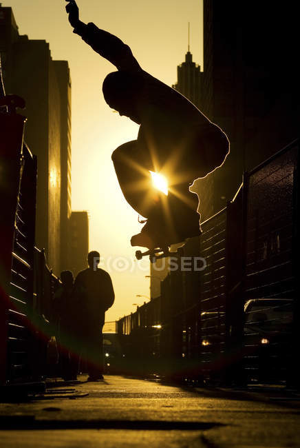Skateboarder performing ollie along street in downtown Toronto at sunset, Ontario, Canada. — Stock Photo