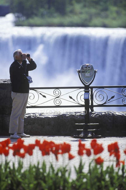 Senior man by American Falls and viewscope, Niagara Falls, Ontário, Canadá . — Fotografia de Stock
