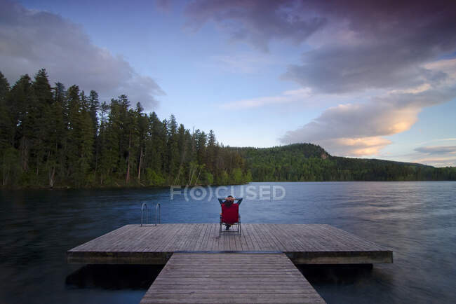 Woman relaxes and watches the sunset from the wharf at Gardom Lake near Salmon Arm, British Columbia, Canada, MR022 — Stock Photo