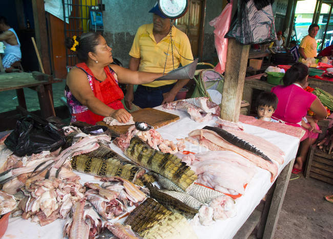 Einheimische am Stand mit Krokodilfleisch in Marktszene von Iquitos in Peru — Stockfoto