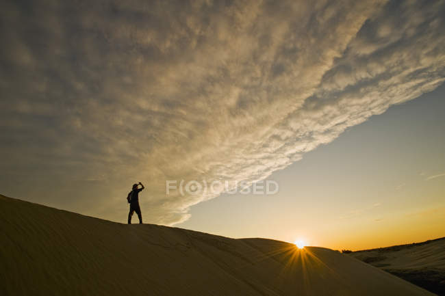 Человек, совершающий пеший поход по дюнам Великого Океана Сэндхиллс на восходе солнца, Скептр, Океан, Канада — стоковое фото