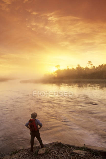 Вид сзади на туриста-мужчину вдоль реки Уайтшелл на восходе солнца, Провинциальный парк Уайтселл, Манитоба, Канада . — стоковое фото