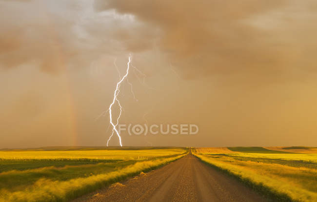 Электрический шторм над гравийной дорогой в сельхозугодицах возле Вал-Мари, Саскачеван, Канада — стоковое фото