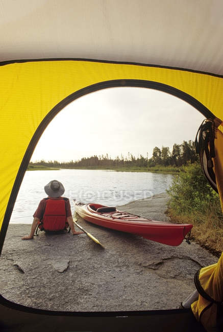 Veduta posteriore del turista maschio che riposa lungo il fiume Whiteshell, Whiteshell Provincial Park, Manitoba, Canada . — Foto stock