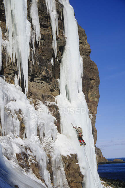 Um escalador de gelo ascendendo a Wiser 's Deluxe WI5, Grand Manan Island, New Brunswick, Canadá — Fotografia de Stock