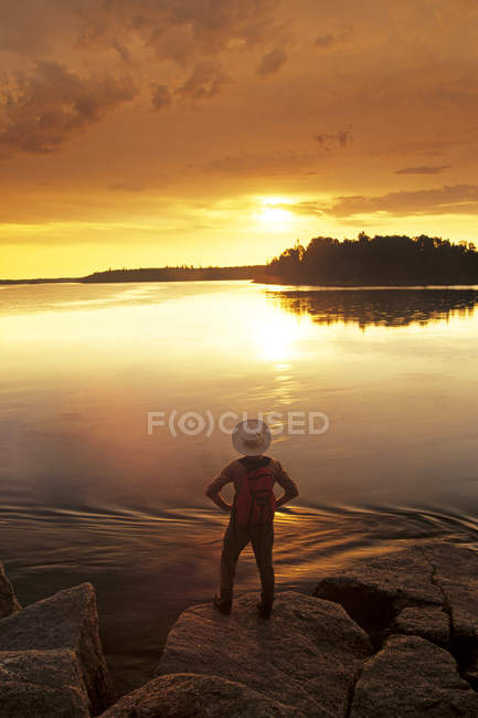 Visão traseira do homem assistindo nascer do sol ao longo do Lago Numau, Parque Provincial Whiteshell, Manitoba, Canadá . — Fotografia de Stock