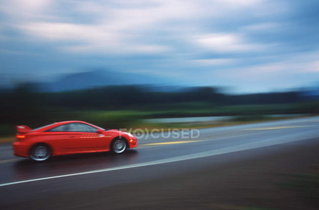 Foto borrosa de coche deportivo rojo en la carretera, Columbia Británica, Canadá . - foto de stock