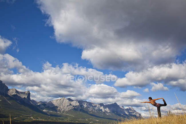 Fit woman practicing yoga on hill in backcountry of Canmore, Canada — Stock Photo