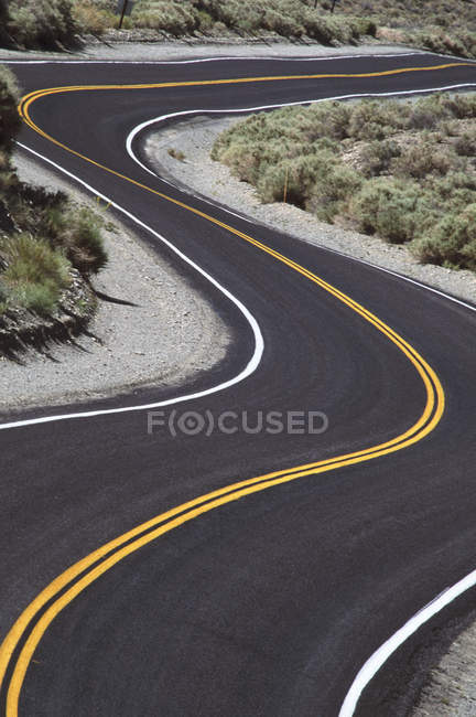 Strada asfaltata tortuosa con linee gialle, British Columbia, Canada . — Foto stock