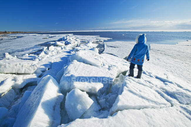 A man with looks out over washed up ice piles, along Lake Winnipeg, Manitoba, Canada — Stock Photo