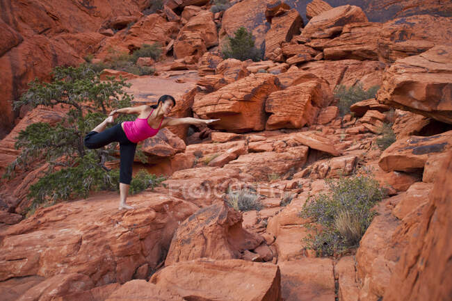 Donna in forma che pratica yoga su rocce rosse del deserto del Mojave, Las Vegas, Nevada, Stati Uniti d'America — Foto stock