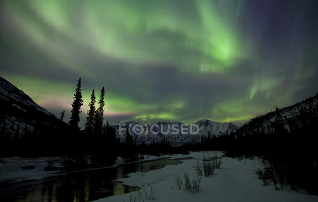 Luci settentrionali sopra le montagne e il fiume Wheaton fuori Whitehorse, Yukon, Canada . — Foto stock