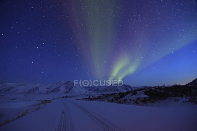 Aurora borealis over snow covered Dempster Highway, Yukon, Canada. — Stock Photo
