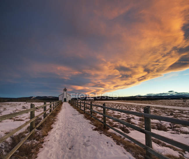 Cloudscape over McDougall Church in snow-covered meadow, Morley, Alberta, Canada — Stock Photo
