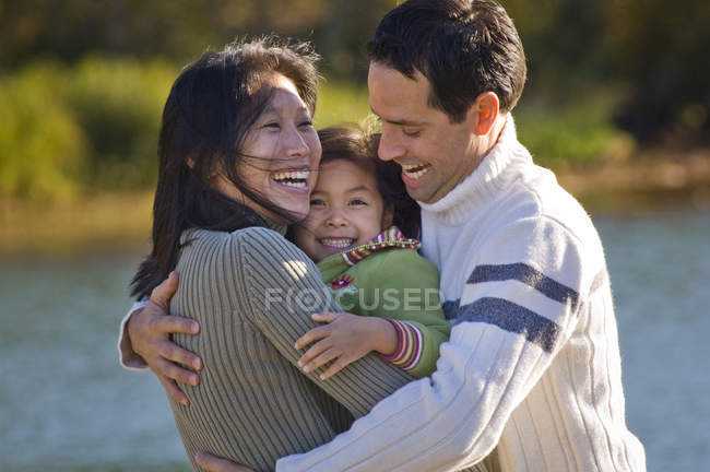 Asian mom and Caucasian dad playing with daughter at Green Lake, Whistler, Canada. — Stock Photo