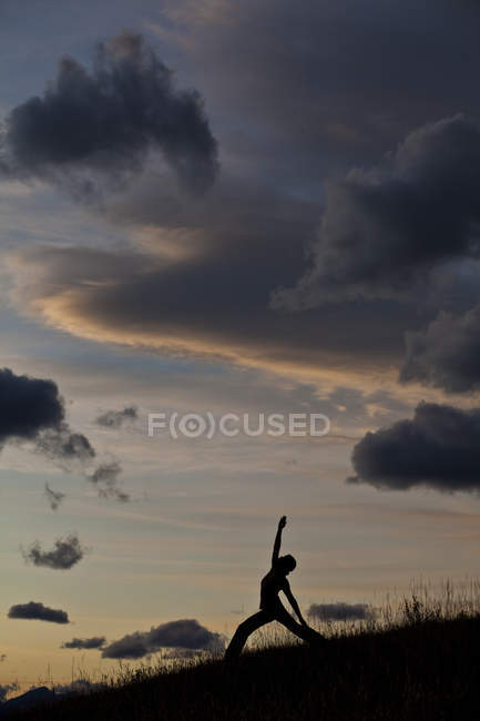 Silhouette of woman practicing yoga on hill at sunrise in Canmore, Alberta, Canada — Stock Photo