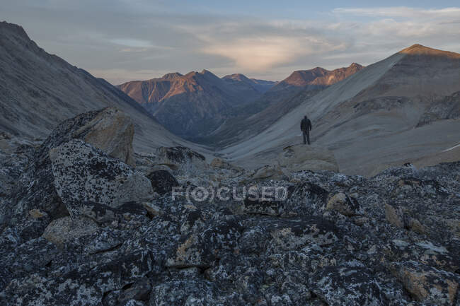 Homem fica em uma rocha ao pôr do sol com vista para Jone 's Pass perto de Carcross, Yukon. — Fotografia de Stock
