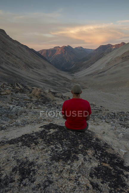 Чоловік сидить на скелі під час заходу сонця з видом на перевал Джоне біля Каркросса, Юкон.. — стокове фото