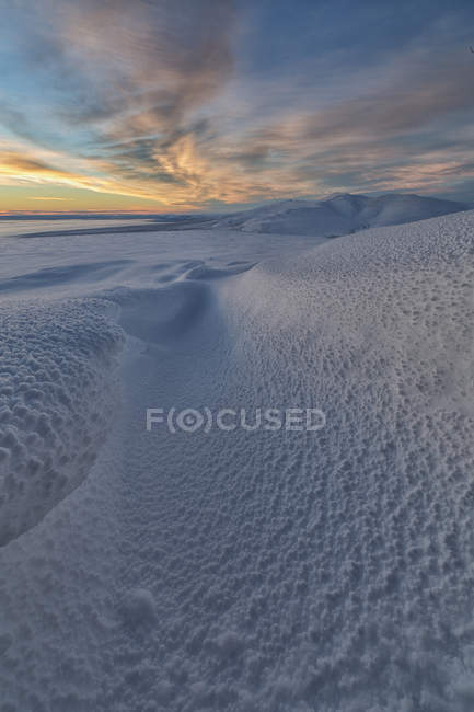 Nubes al atardecer sobre tundra cubierta de nieve y laderas de Crow Mountain, Old Crow, Yukon . - foto de stock