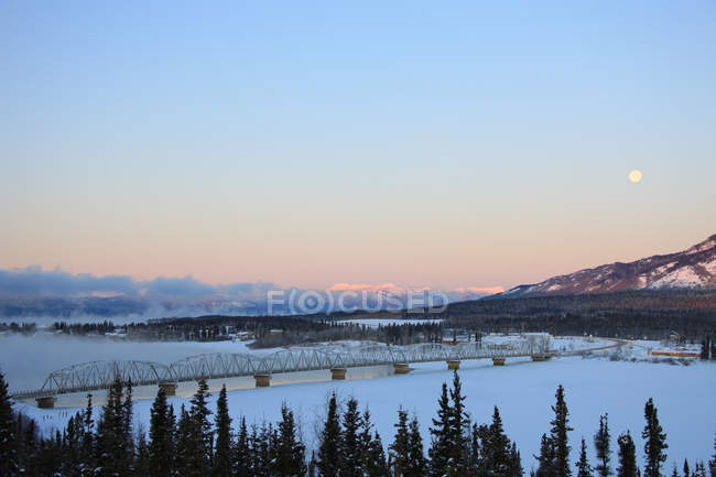 Morgendämmerung über winterliche teslin und teslin bridge, yukon, canada. — Stockfoto