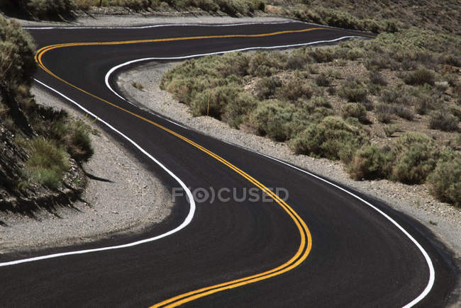 Strada asfaltata tortuosa con linee gialle, British Columbia, Canada . — Foto stock