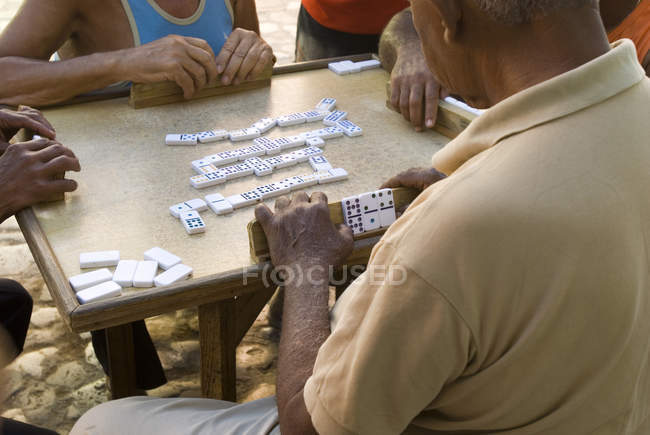 Groupe de messieurs de haut niveau jouant au jeu des dominos dans la rue de Trinidad, Cuba — Photo de stock