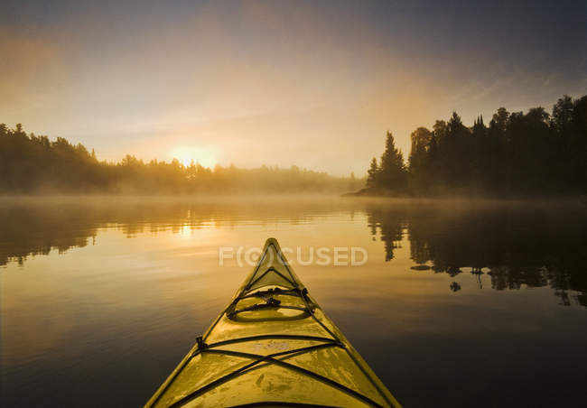 Kayak en el agua durante la mañana brumosa en el lago de Woods, noroeste de Ontario, Canadá - foto de stock