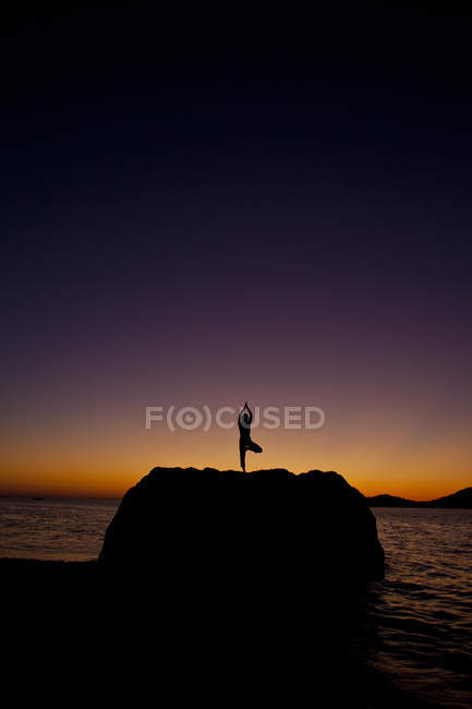 Силует жінка заняттях йогою на прибережні скелі на сході сонця на острові Kalymnos, Греція. — стокове фото