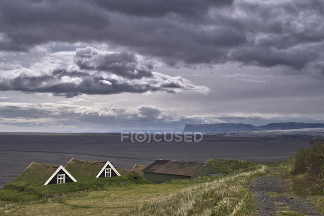 Casas rurales con glaciar Vatnajkull en el fondo, Parque Nacional Vatnajkull, Islandia - foto de stock