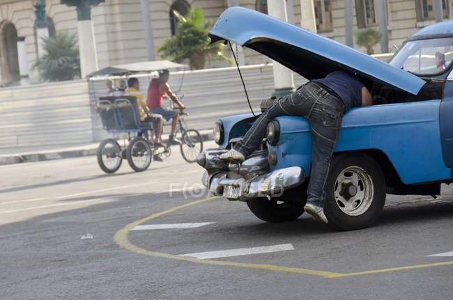 Uomo che lavora su una vecchia auto sulla strada dell'Avana, Cuba — Foto stock