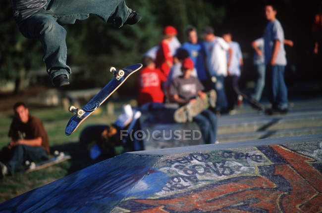 Skateboarder kickfliping board über pyramide in graffiti lackiertem skatepark, leiter, britisch columbia, kanada. — Stockfoto