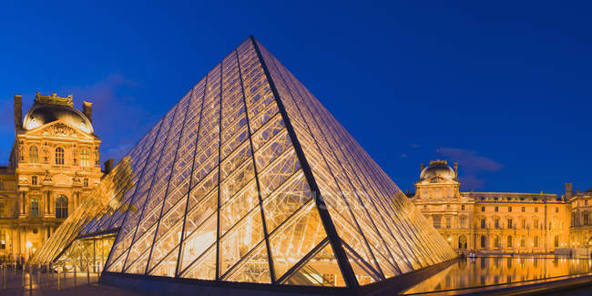 Pirámide del Louvre iluminada por la noche en París, Francia - foto de stock