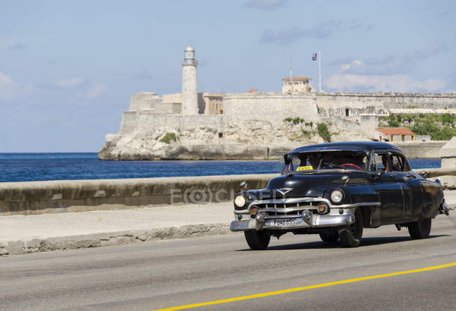 Ретро-американський автомобіль їзда вздовж Малекон з мальовничими видами на прилеглу Morro замку-фортеці, Гавана затока, Гавана, Куба — стокове фото