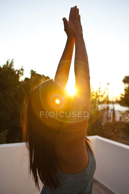 Mulher praticando ioga fora do edifício ao pôr do sol em Kalymnos, Grécia — Fotografia de Stock