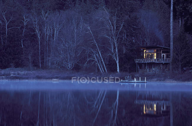Cabina Gunflint Lake illuminata al crepuscolo, Cortes Island, Vancouver Island, British Columbia, Canada . — Foto stock
