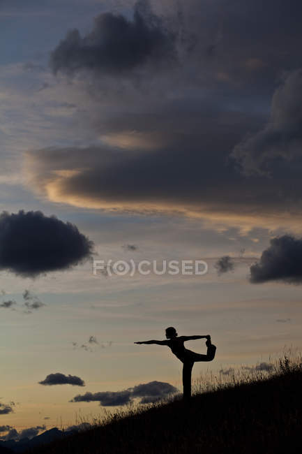 Силуэт женщины, практикующей йогу на холме на восходе солнца в Канморе, Альберта, Канада — стоковое фото