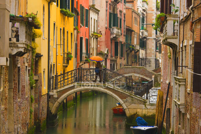 Person mit Regenschirm läuft auf Brücke über Kanal, Venedig, Italien — Stockfoto