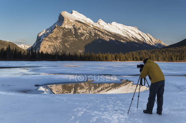 Fotógrafo compondo uma fotografia de Rundle Mount em Vermilion Lakes congelados no inverno em Banff National Park, Alberta, Canadá. — Fotografia de Stock