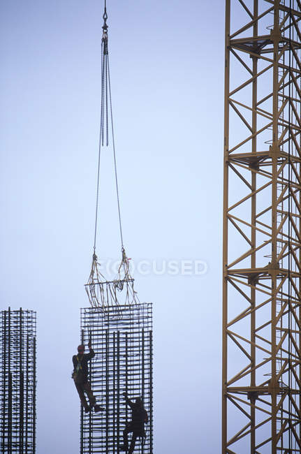 Steelworkers in silhouette while tying steel in column on construction site, British Columbia, Canada. — Stock Photo