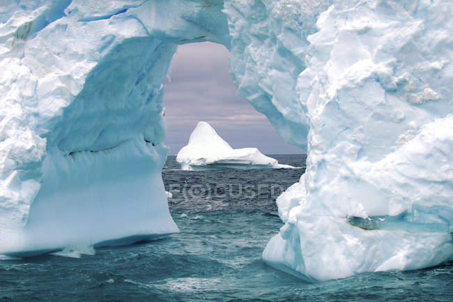 Айсберг и природная ледяная арка в море Уэдделла, Антарктида — стоковое фото
