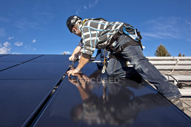 Dos instaladores de paneles solares instalan paneles solares en el techo, las estribaciones de Alberta cerca de Black Diamond, Alberta, Canadá. - foto de stock