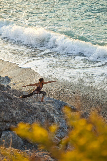 Visão de alto ângulo da mulher fazendo ioga ao pôr do sol perto da praia em Kalymnos, Grécia — Fotografia de Stock