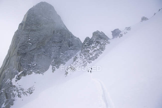 Siluetas de esquiadores de backcountry bajo Snowpatch Spire, Bugaboos, Columbia Británica, Canadá. - foto de stock